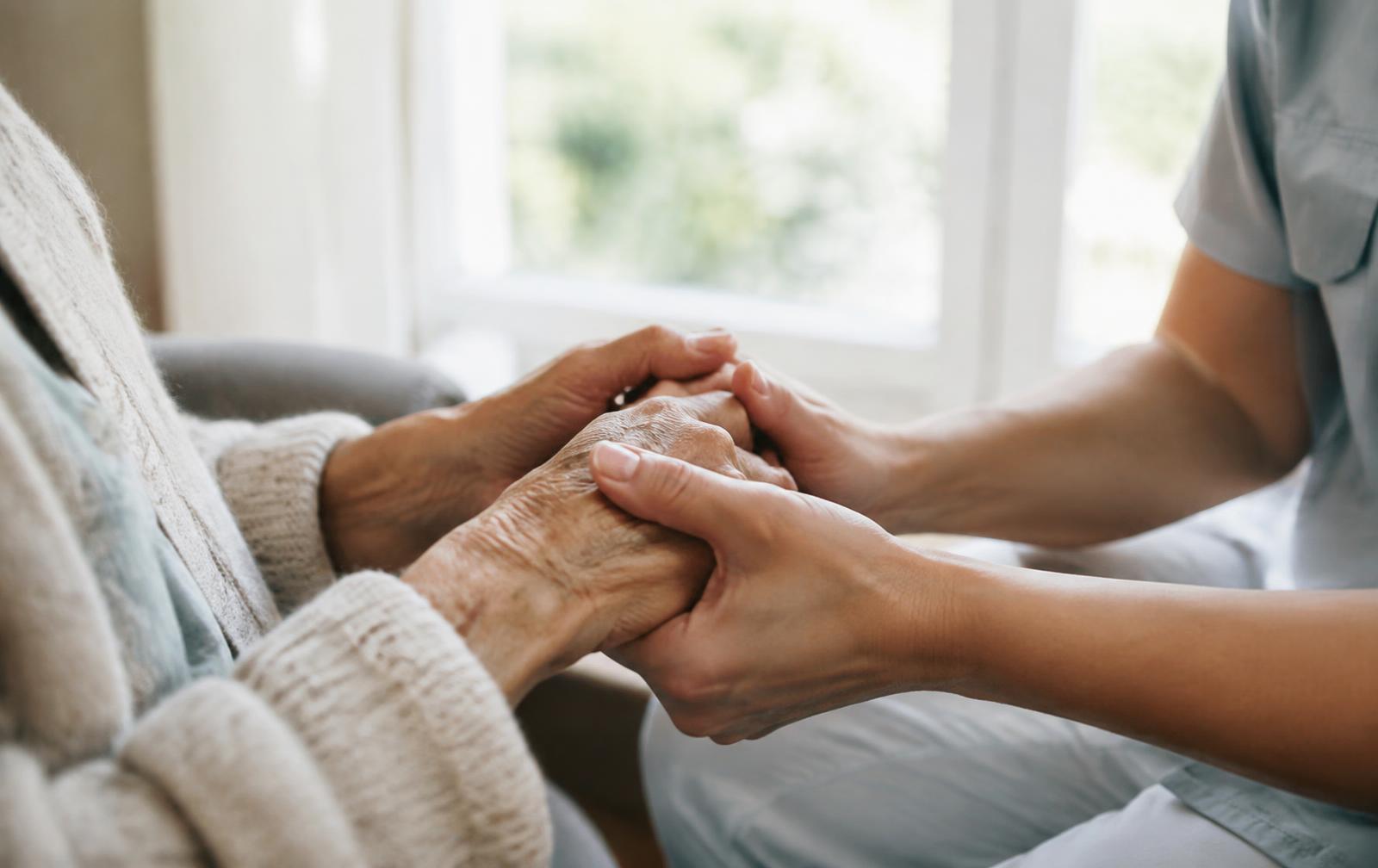 Mains d'une personne âgée tenues par celles d'une soignante