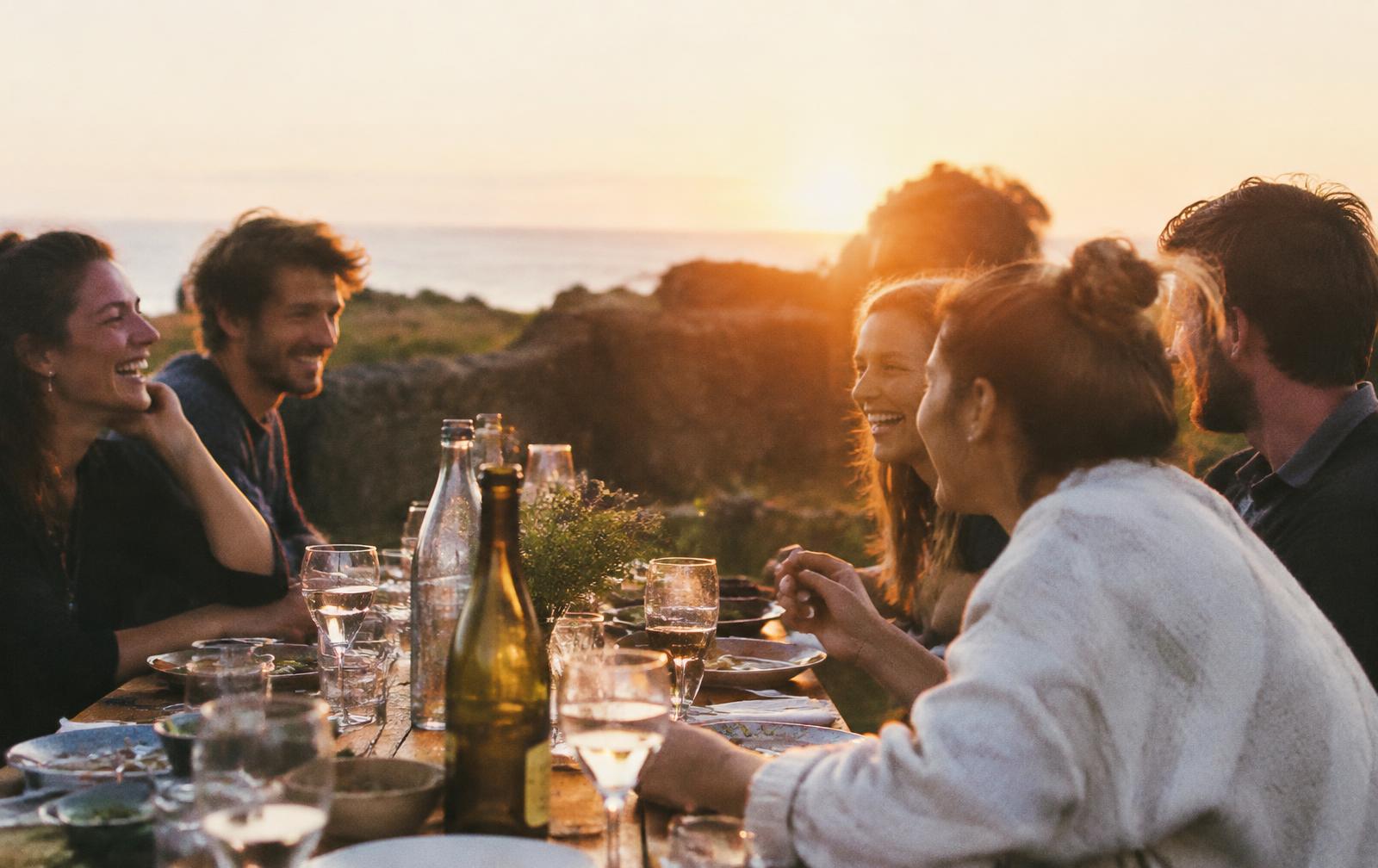 Amis partageant un repas en extérieur au coucher du soleil